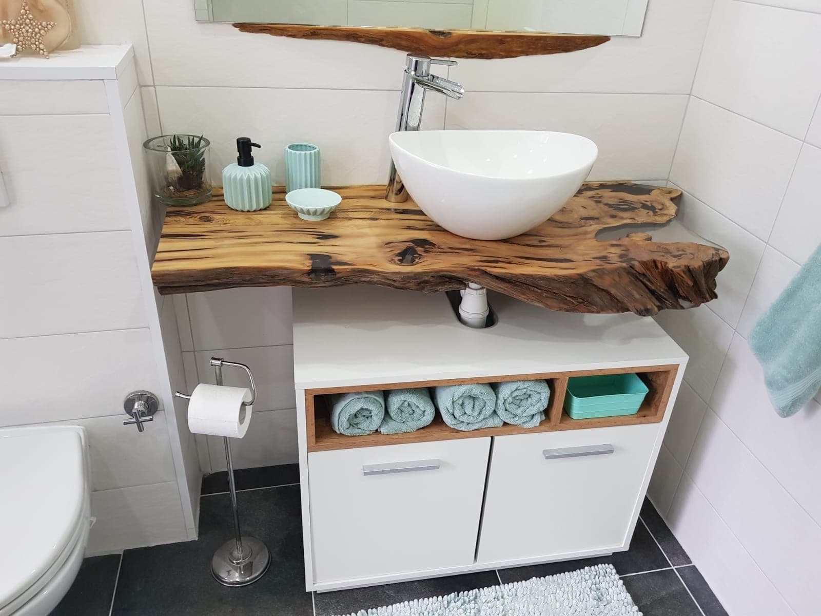 Waschtischplatte aus Zedern-Treibholz mit unregelmäßiger Kante und weißem Aufsatzbecken über einem weißen Schrank mit Handtuchfach.